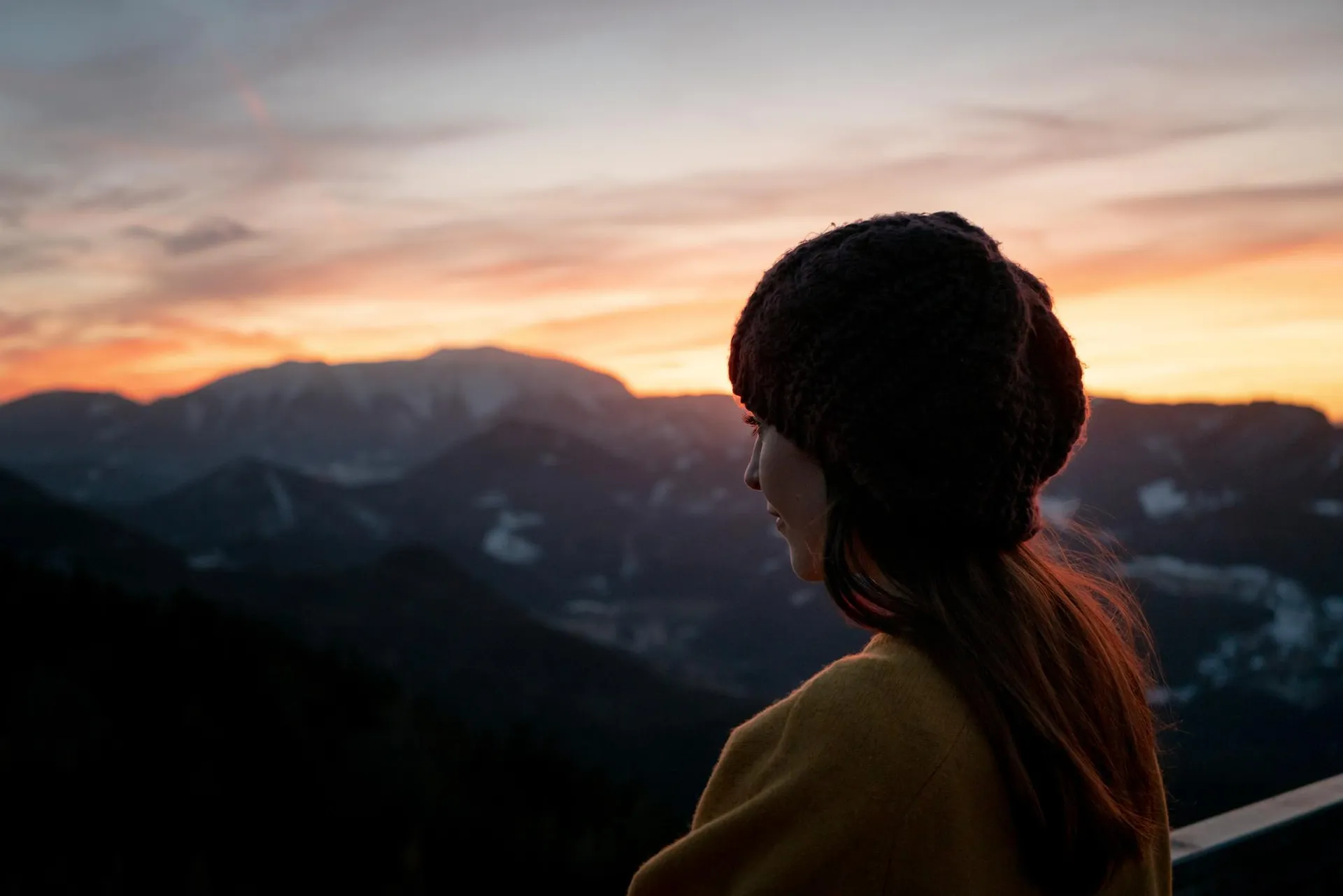 Mujer contemplando el atardecer sobre las montañas